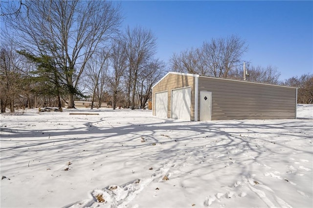 snow covered garage featuring a detached garage