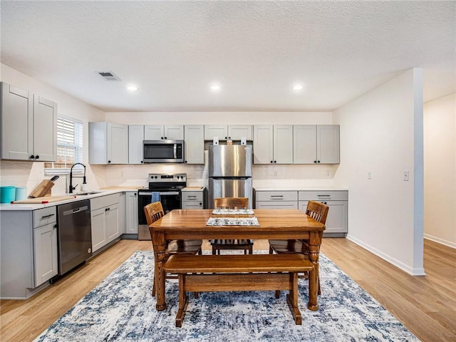 kitchen with sink, gray cabinets, stainless steel appliances, and light hardwood / wood-style floors