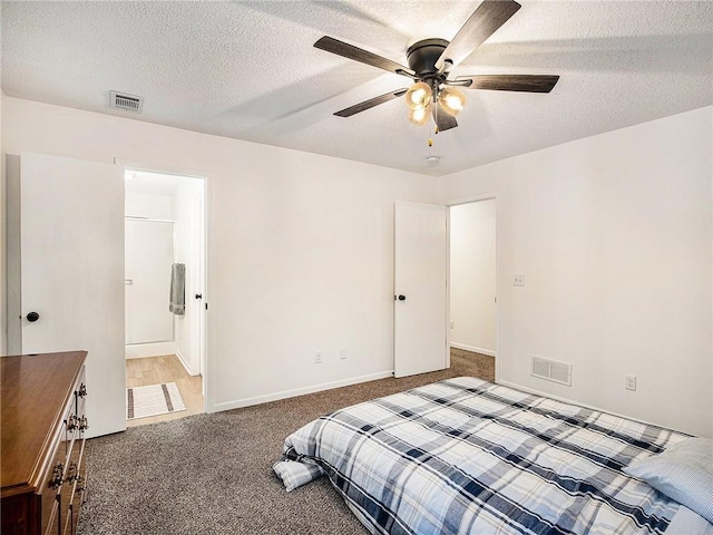 bedroom featuring ceiling fan, carpet, ensuite bathroom, and a textured ceiling