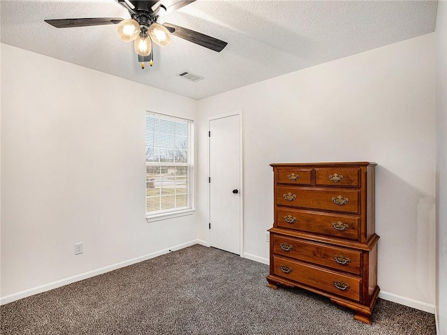 unfurnished bedroom with ceiling fan, dark carpet, and a textured ceiling