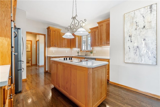 kitchen with a kitchen island, black electric cooktop, a sink, and light countertops