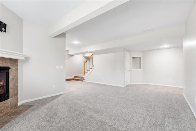 unfurnished living room with stairs, a fireplace, baseboards, and carpet flooring