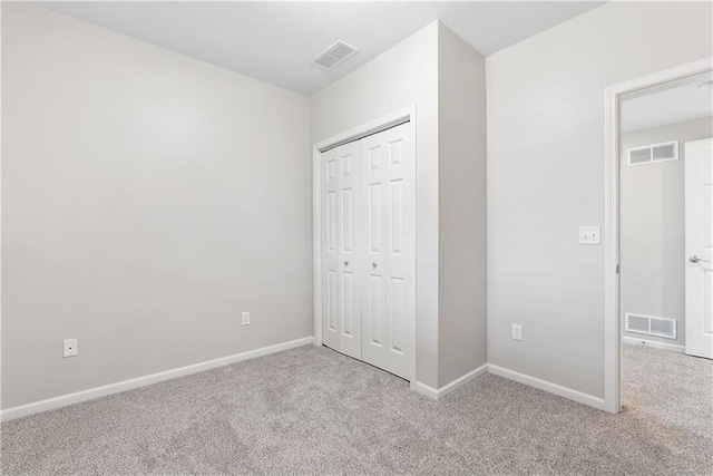 unfurnished bedroom with carpet floors, baseboards, and visible vents