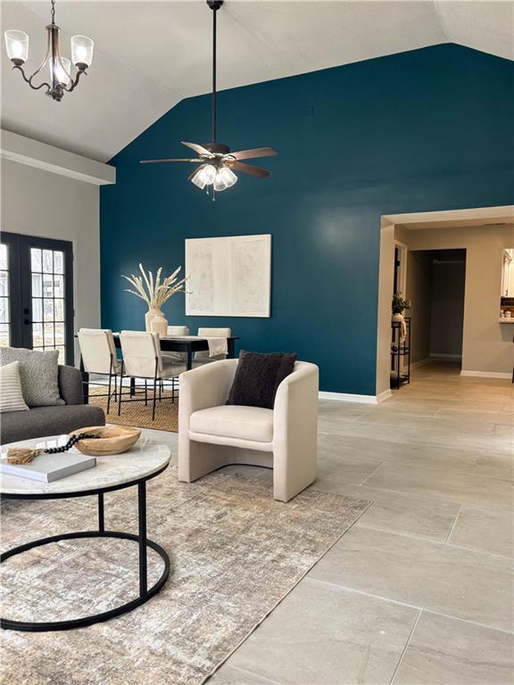 living room with vaulted ceiling and ceiling fan with notable chandelier