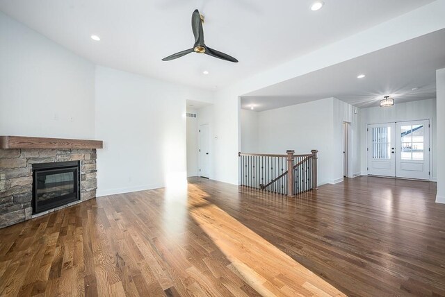 unfurnished living room featuring a fireplace, dark hardwood / wood-style floors, ceiling fan, and french doors