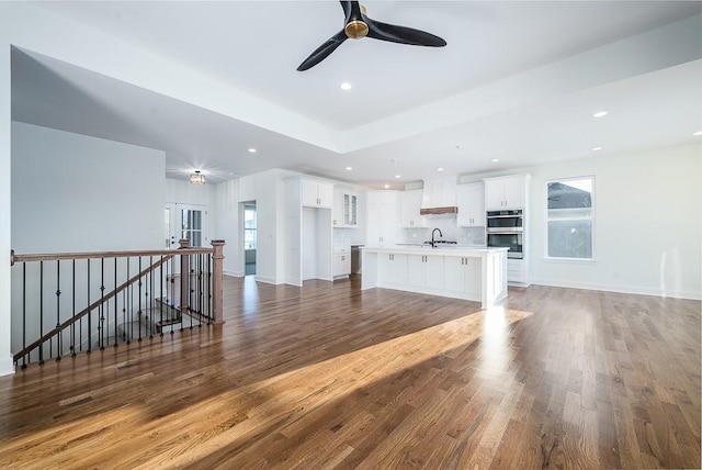 unfurnished living room featuring a healthy amount of sunlight, sink, ceiling fan, and dark hardwood / wood-style floors