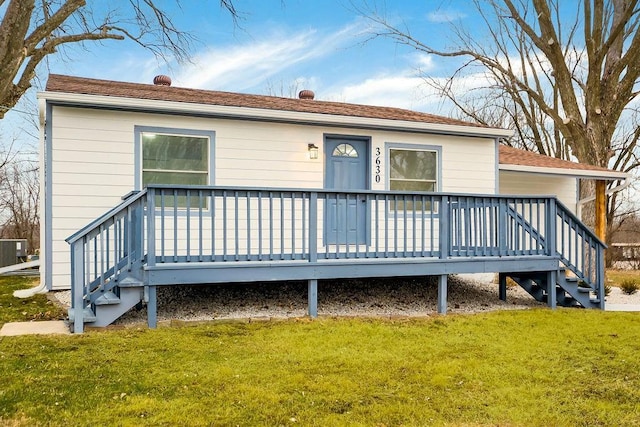 rear view of house with a wooden deck, a yard, and central AC