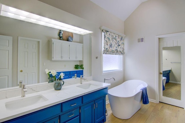 bathroom with vanity, vaulted ceiling, wood-type flooring, and a tub