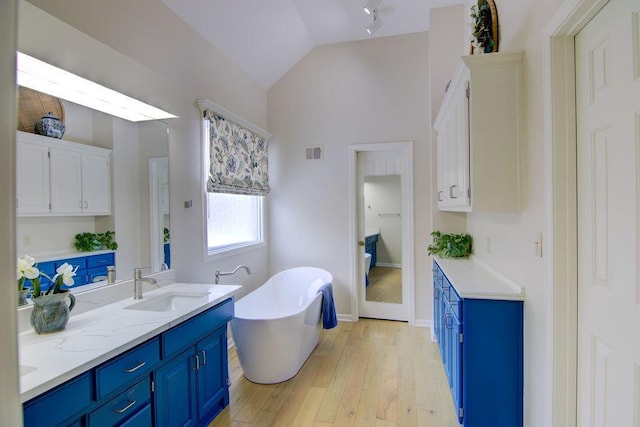 bathroom featuring hardwood / wood-style flooring, lofted ceiling, a washtub, and vanity