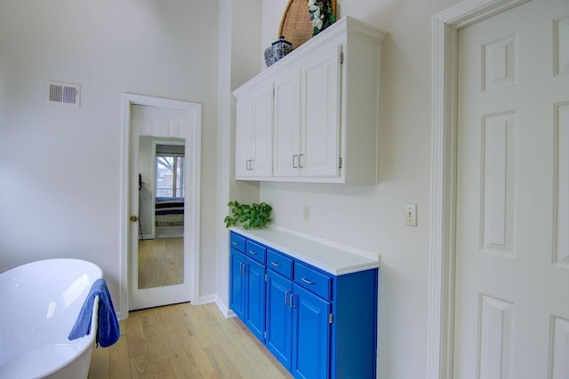 bar featuring white cabinets, light wood-type flooring, and blue cabinetry