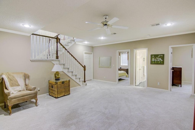 living area with a textured ceiling, ornamental molding, light carpet, and ceiling fan