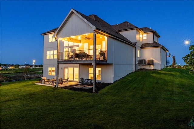 14616 Aspen Cir, Basehor, KS 66007 - back of house at night with a balcony, a lawn, a patio, a ceiling fan, and central AC