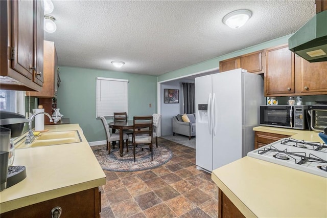 kitchen featuring extractor fan, white refrigerator with ice dispenser, sink, and a textured ceiling