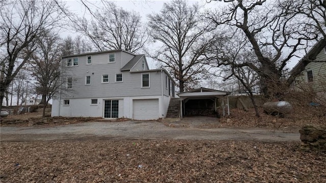 view of front facade featuring a garage, dirt driveway, and a carport