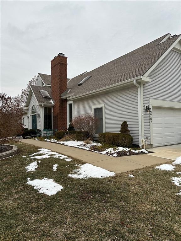 view of home's exterior with an attached garage, roof with shingles, and a chimney