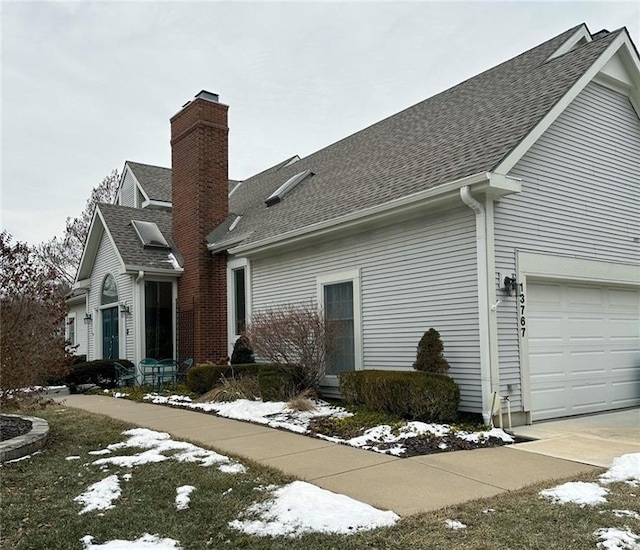 snow covered property with a shingled roof and a chimney