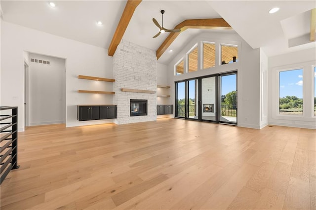 unfurnished living room featuring high vaulted ceiling, ceiling fan, light wood-style flooring, a fireplace, and baseboards