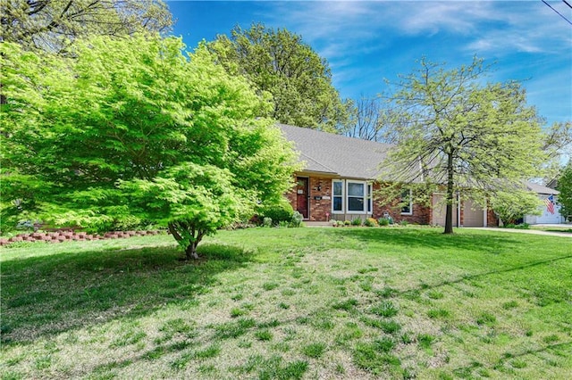view of front facade with a front lawn, an attached garage, and brick siding