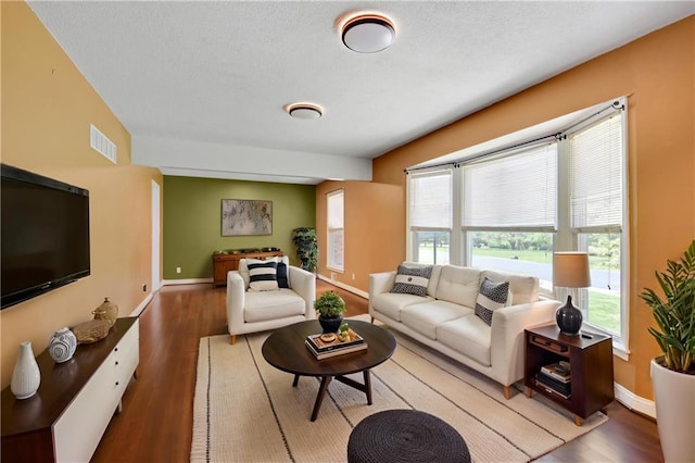 living area with wood finished floors, visible vents, and baseboards