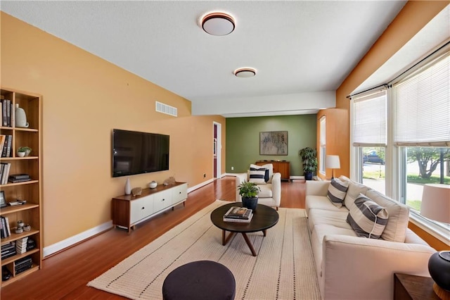 living area featuring baseboards, visible vents, and wood finished floors