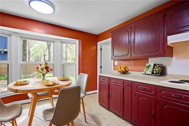 kitchen featuring decorative backsplash, under cabinet range hood, white electric stovetop, light countertops, and dark brown cabinets