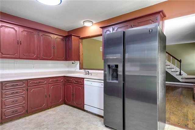kitchen featuring a sink, light countertops, dishwasher, and stainless steel fridge with ice dispenser