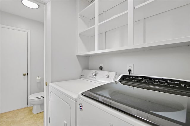laundry area featuring light tile patterned floors, baseboards, laundry area, and washer and clothes dryer