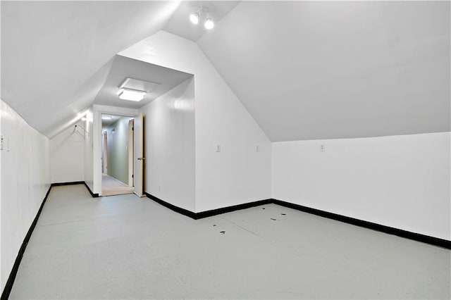 additional living space with concrete floors, vaulted ceiling, and baseboards