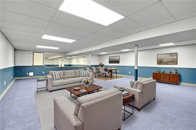 carpeted living area featuring baseboards and a drop ceiling