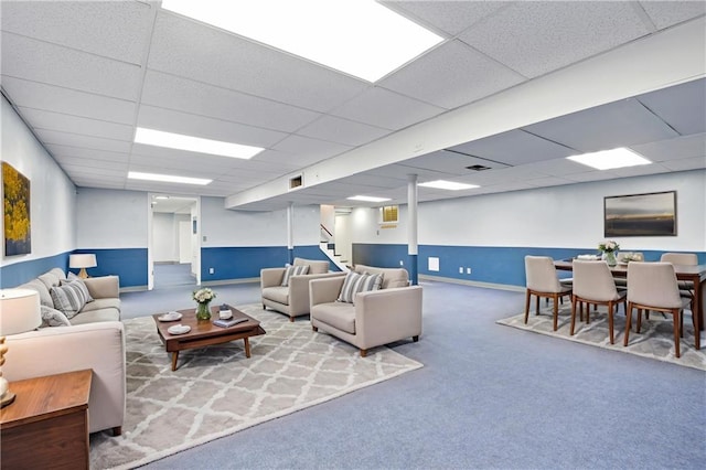 living area featuring stairway, a paneled ceiling, carpet, and baseboards