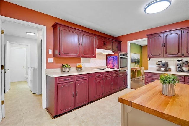 kitchen with separate washer and dryer, light countertops, stainless steel oven, and backsplash