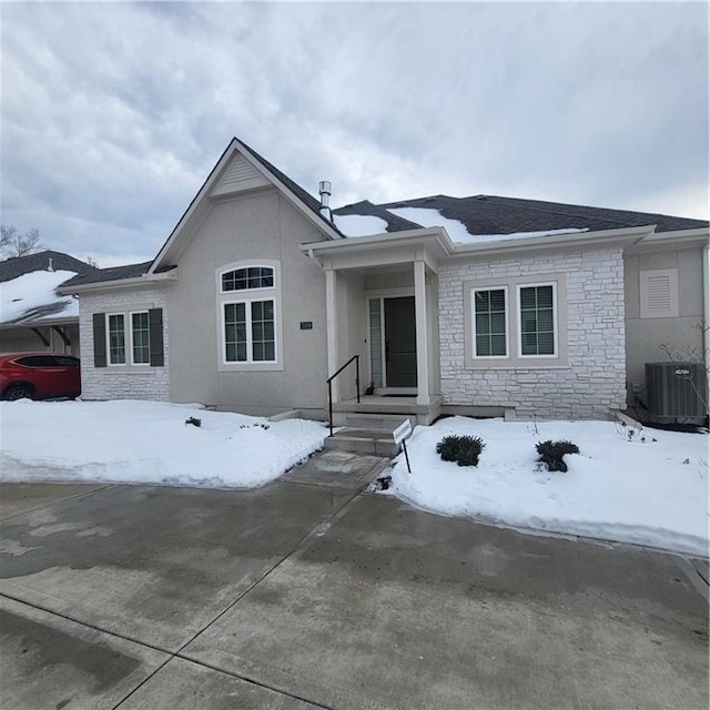 ranch-style house with central air condition unit, stone siding, and stucco siding