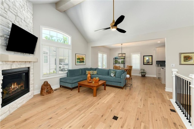 7209 Allman Dr, Shawnee, KS 66217 - living room with a stone fireplace, plenty of natural light, ceiling fan, light wood-style flooring, and high vaulted ceiling