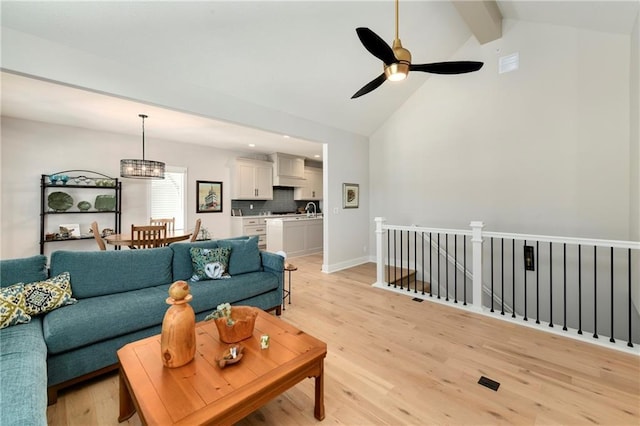 7209 Allman Dr, Shawnee, KS 66217 - living room with light wood-style floors, beamed ceiling, ceiling fan, high vaulted ceiling, and a chandelier