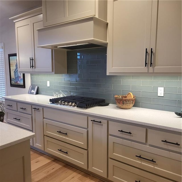 7209 Allman Dr, Shawnee, KS 66217 - kitchen featuring premium range hood, stainless steel gas stovetop, light wood-style flooring, and tasteful backsplash
