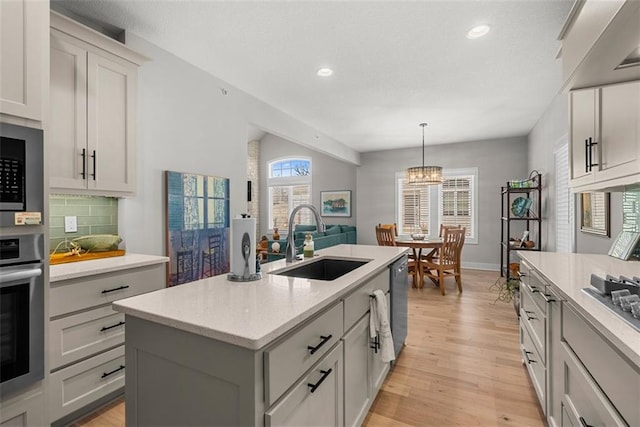 7209 Allman Dr, Shawnee, KS 66217 - kitchen with a sink, stainless steel oven, an island with sink, tasteful backsplash, and light wood finished floors