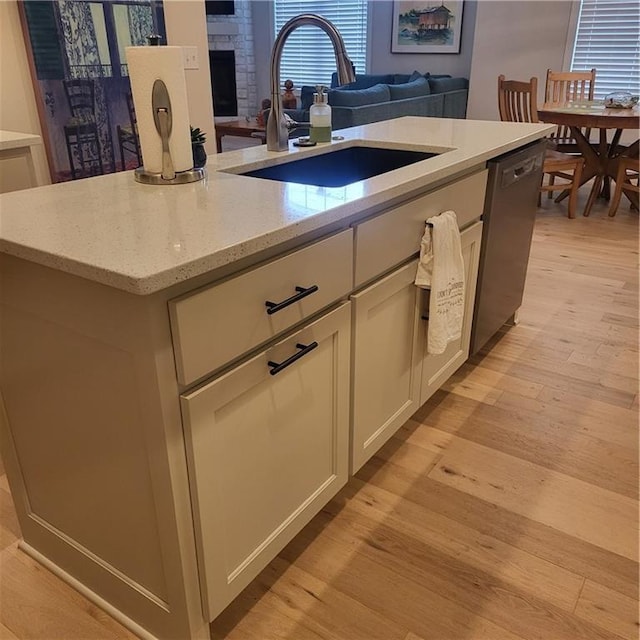 7209 Allman Dr, Shawnee, KS 66217 - kitchen featuring stainless steel dishwasher, light wood-type flooring, a sink, open floor plan, and light stone countertops