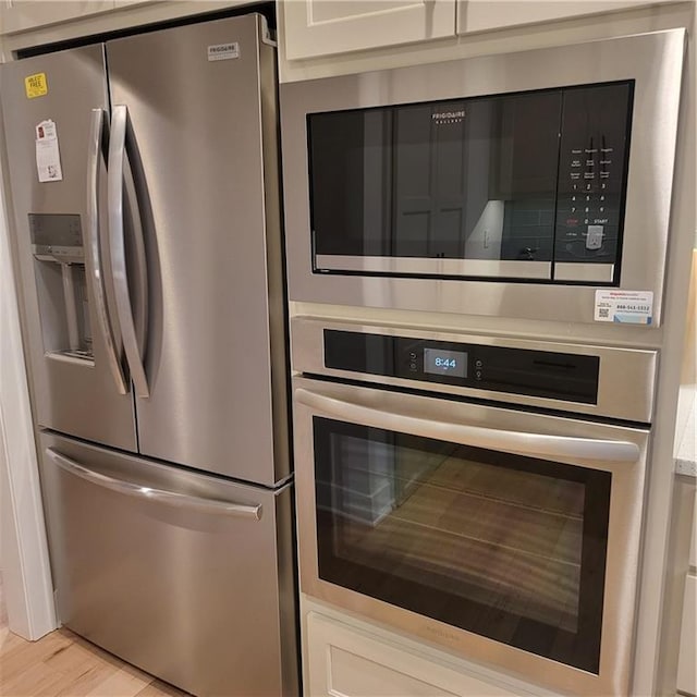 7209 Allman Dr, Shawnee, KS 66217 - kitchen with stainless steel appliances, white cabinets, light wood-type flooring, and light countertops