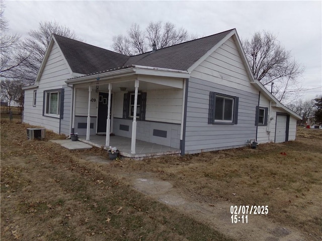 view of side of property featuring a garage, central air condition unit, and covered porch