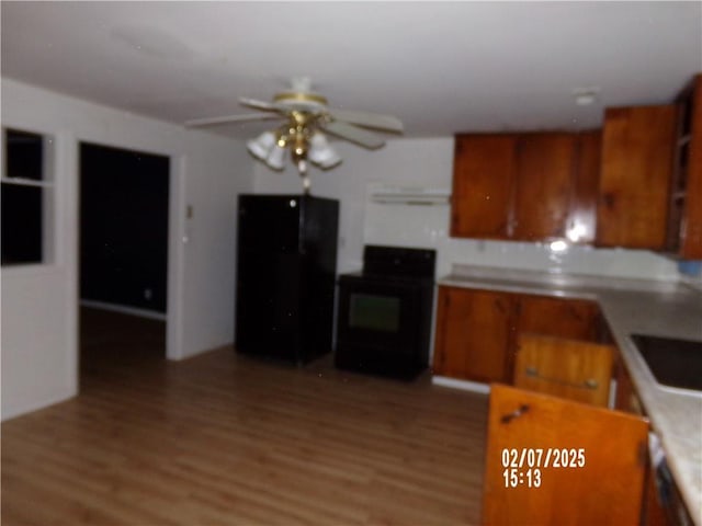 kitchen featuring ceiling fan, stove, black fridge, and light hardwood / wood-style floors