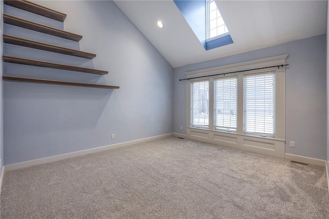 unfurnished room featuring a skylight, recessed lighting, light colored carpet, high vaulted ceiling, and baseboards