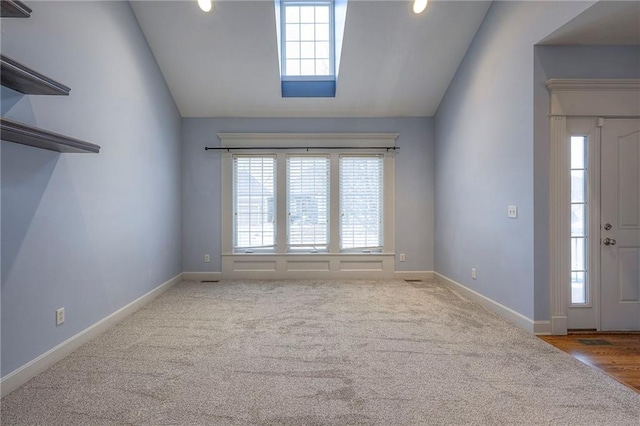 empty room featuring lofted ceiling, a healthy amount of sunlight, and baseboards