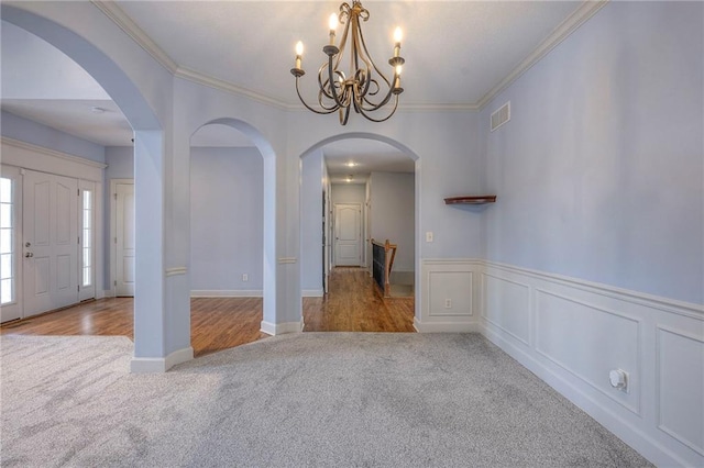 interior space with arched walkways, light colored carpet, visible vents, an inviting chandelier, and crown molding