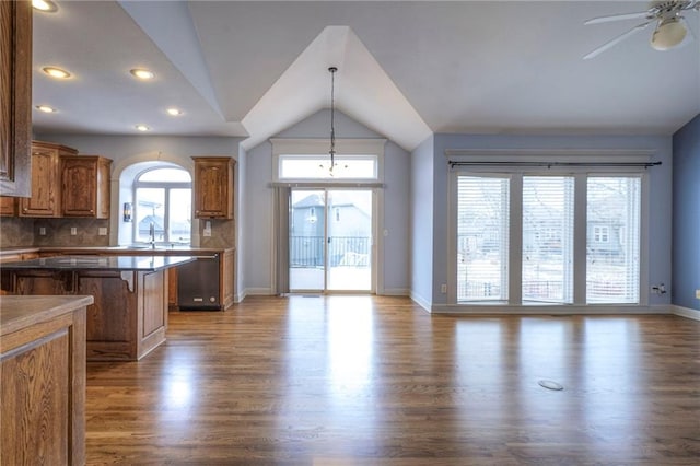 kitchen with dark countertops, open floor plan, brown cabinets, and a kitchen bar