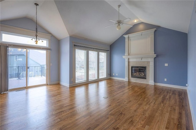 unfurnished living room with a tile fireplace, wood finished floors, a ceiling fan, baseboards, and vaulted ceiling