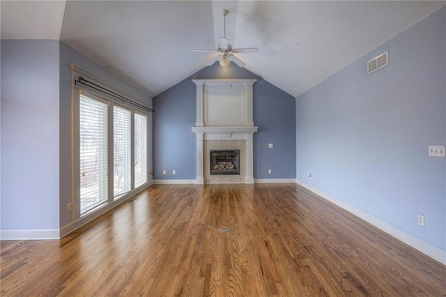 unfurnished living room with baseboards, visible vents, a tiled fireplace, a ceiling fan, and wood finished floors