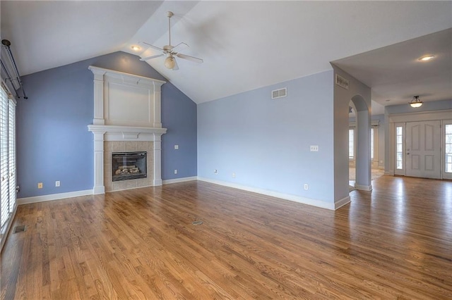 unfurnished living room with visible vents, wood finished floors, a ceiling fan, and a tile fireplace