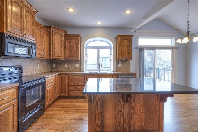 kitchen featuring black appliances, a breakfast bar area, a sink, and a center island