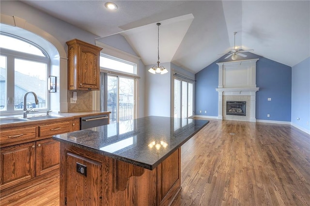 kitchen with a sink, open floor plan, a center island, dishwasher, and brown cabinetry