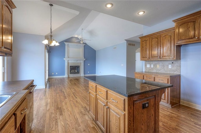 kitchen with open floor plan, light wood-style flooring, brown cabinetry, and visible vents